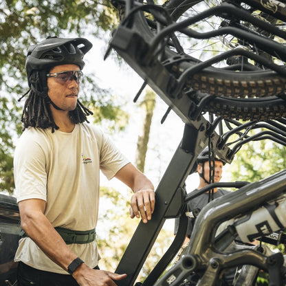 Person loading a bike onto a hitch bike rack with multiple cradles
