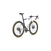 Road bike side view with blue-and-white frame, deep wheels, disc brakes, gold rim trim