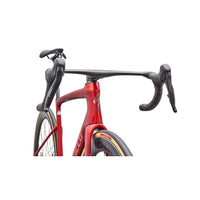 Red road bike close-up showing handlebars, fork, and integrated frame shape