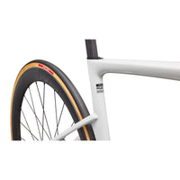 Front wheel and fork detail on white road bike with orange-trim tire sidewall