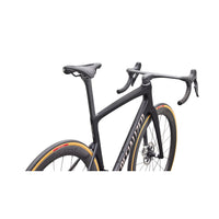 Road bike cockpit close-up with black frame and drop handlebars, gold rim accents