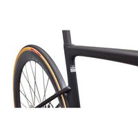 Road bike front wheel and black frame with gold rim accents