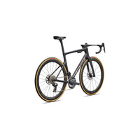 Road bike side view with black frame and gold rim trim, visible drivetrain and wheels