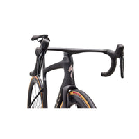 Road bike frame detail with matte black finish, drop handlebar and orange tire edge