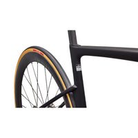 Road wheel and fork on matte black road bike, orange-accent tire and rim