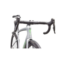 Silver road bike cockpit with black handlebars and brake hoods, green accent on frame