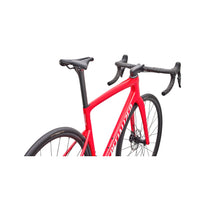Red road bike with drop handlebars, front wheel, and black saddle