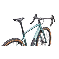 Teal gravel bike close-up of front end with drop handlebars and tan sidewall tires.