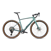 Teal gravel bike with drop handlebars, disc brakes, and tan sidewall tires.