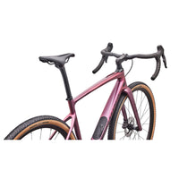 Gravel road bike close-up: pink metallic frame, black handlebars, disc front wheel
