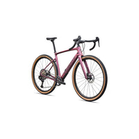 Pink gravel bike three-quarter view with drop handlebars and tan sidewall tires.