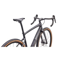 Gravel road bike close-up: dark gray frame, drop handlebars, disc front wheel, tan trim