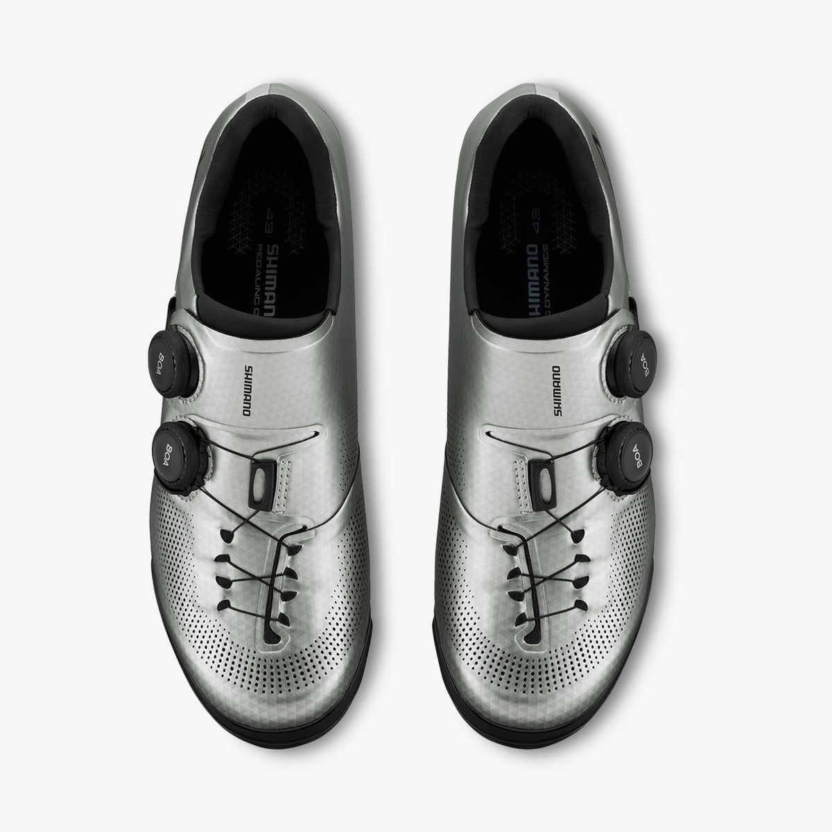 Pair of silver cycling shoes with black BOA dials, lace-like details, and perforations