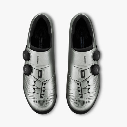 Pair of silver cycling shoes with black BOA dials, lace-like details, and perforations