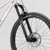 Front suspension fork and knobby tire on a white full-suspension bike