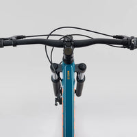Front view of teal 26 in mountain bike handlebars, grips, and suspension fork