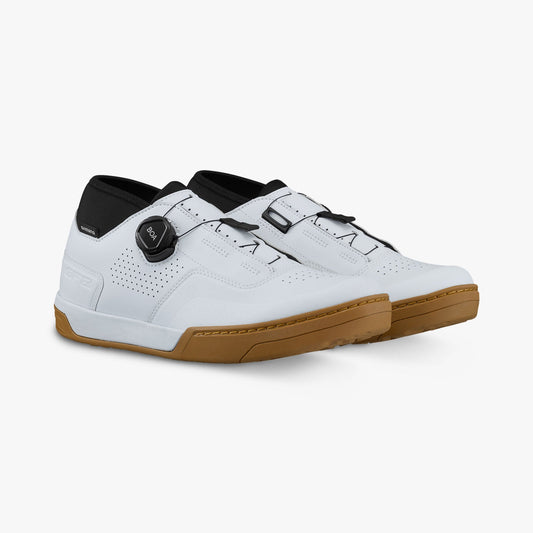 White cycling shoe with perforated upper and adjustable strap; honeycomb rubber sole