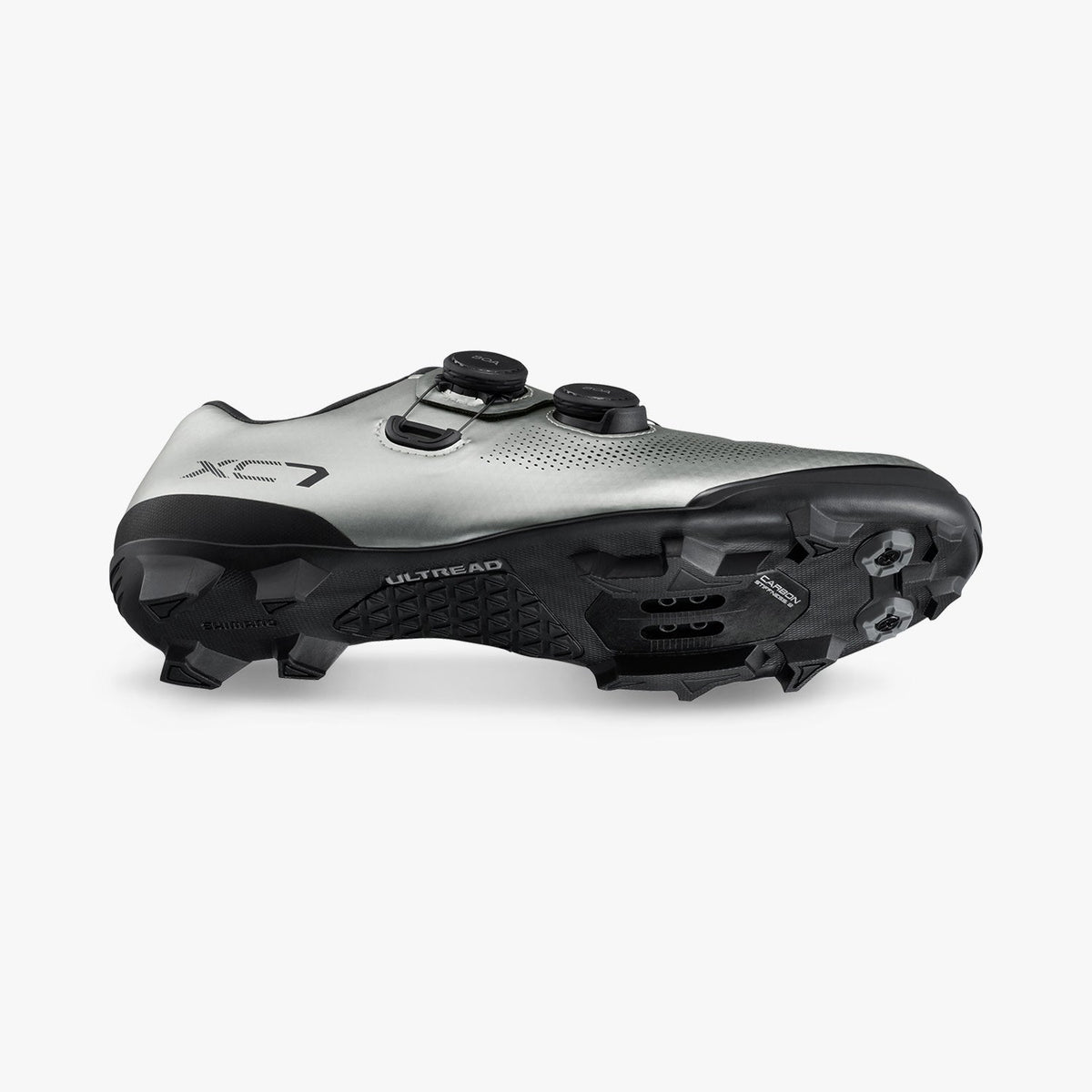Silver cycling shoe side view showing black traction lugs and cleat hardware
