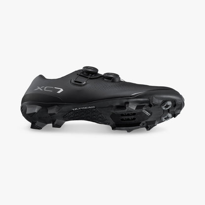Black cycling cleat shoe side view with cleat plate and studded heel outsole